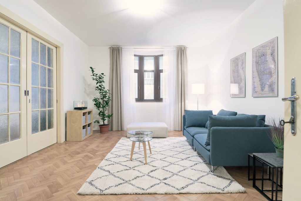 zařízený obývací pokoj s posuvnými dveřmi , oknem, modrou sedačkou a kobercem